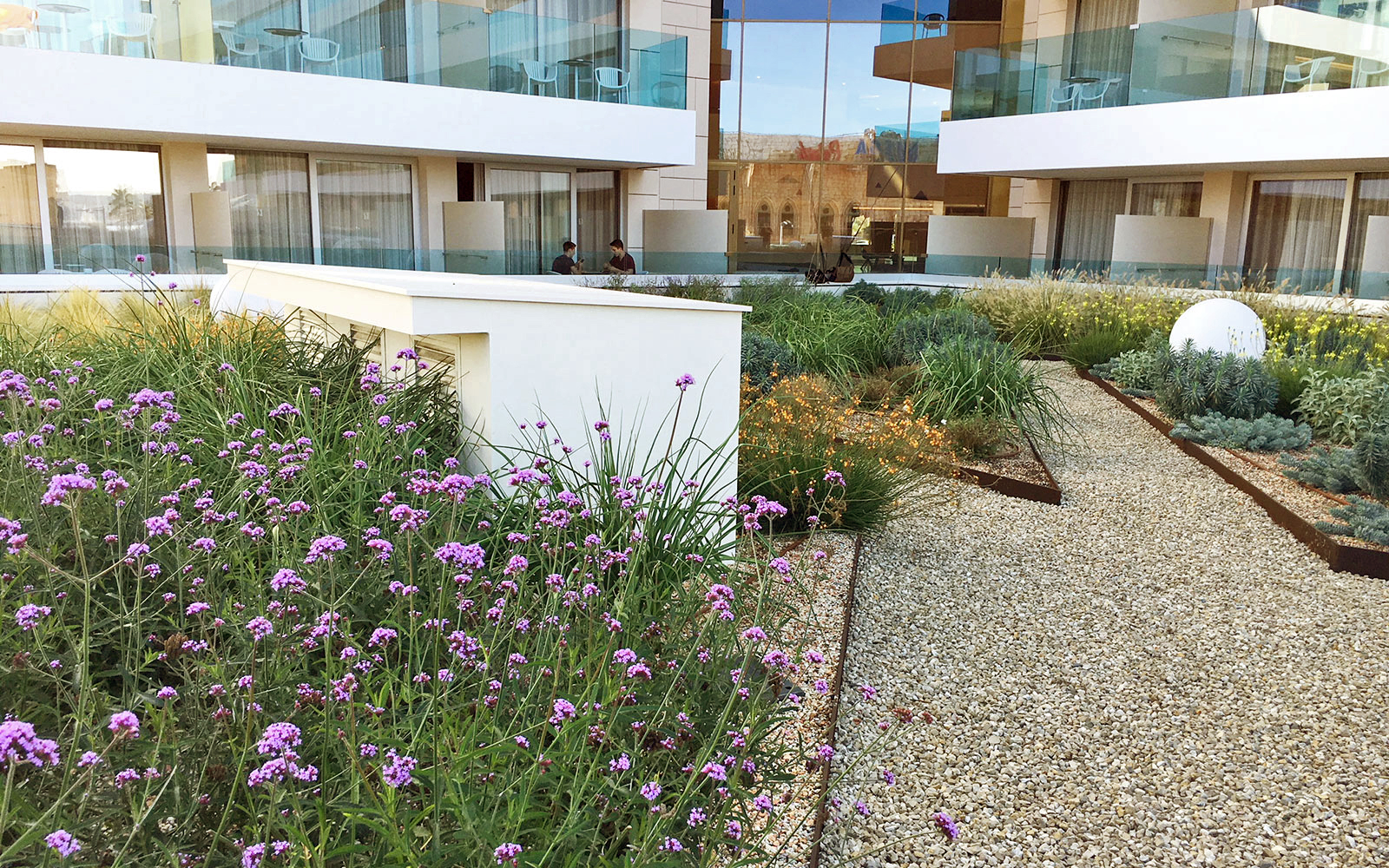 The selected plants were chosen with respect to a high tolerance to water stress and solar radiation. Roof garden with flower beds and a gravel path